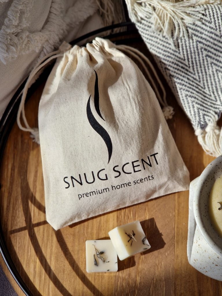 Snug Scent cotton pouch with natural wax melts on a wooden tray