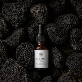 Bergamot & Bay pure essential oil blend bottle resting on natural lava stones