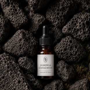 Jasmine & Sandalwood pure essential oil blend bottle resting on natural lava stones