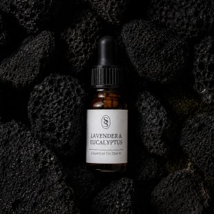 Lavender & Eucalyptus pure essential oil blend bottle resting on natural lava stones