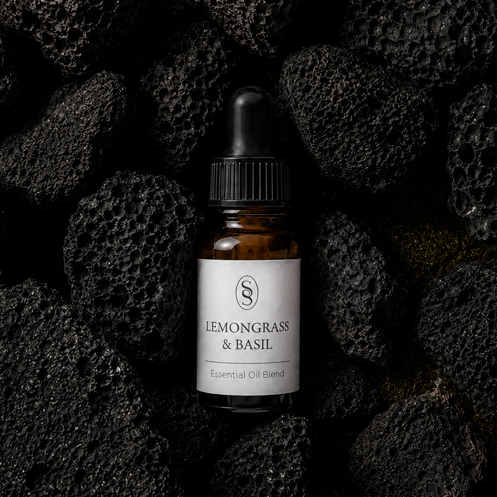 Lemongrass & Basil pure essential oil blend bottle resting on natural lava stones