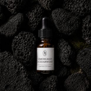 Lemongrass & Cedarwood pure essential oil blend bottle resting on natural lava stones