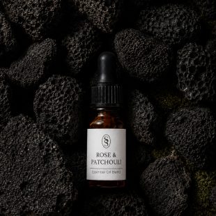 Rose & Patchouli pure essential oil blend bottle resting on natural lava stones