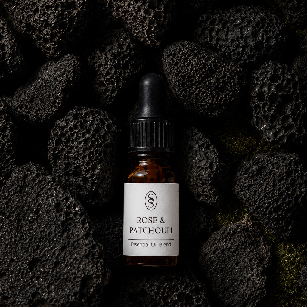 Rose & Patchouli pure essential oil blend bottle resting on natural lava stones